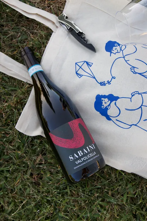 Una bottiglia di Valpolicella appoggiata sulla borsa di tela di UniDomani.
